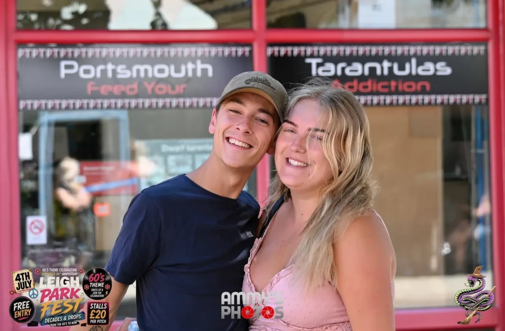 Two smiling visitors posing together outside a shop.