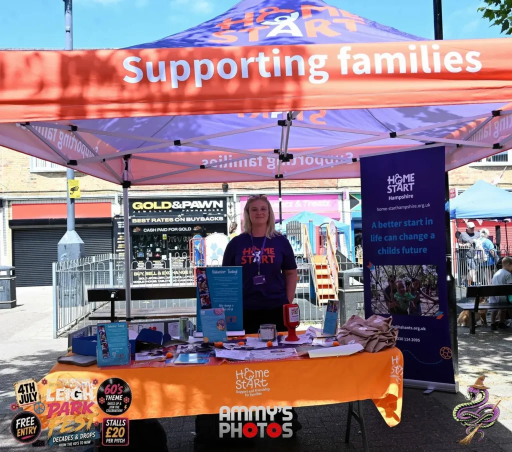 Home-Start information stall beneath an orange Supporting families canopy.