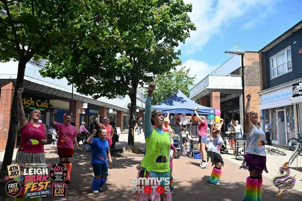 Festival participants dancing in colourful outfits along the pedestrian shopping area.